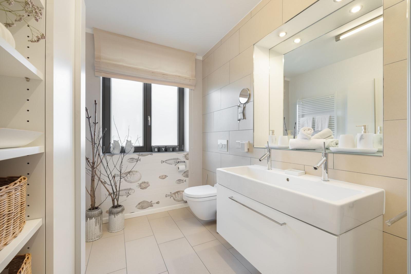 Bathroom with sink, mirror, toilet, and window.
