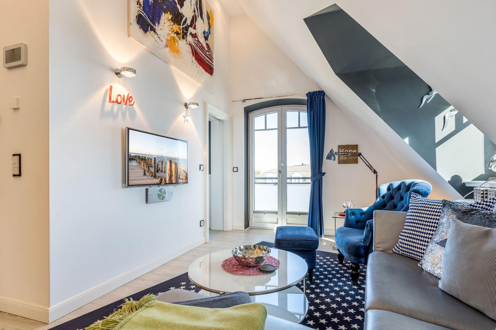 Living area with sofa, armchair, and TV under sloped ceiling.