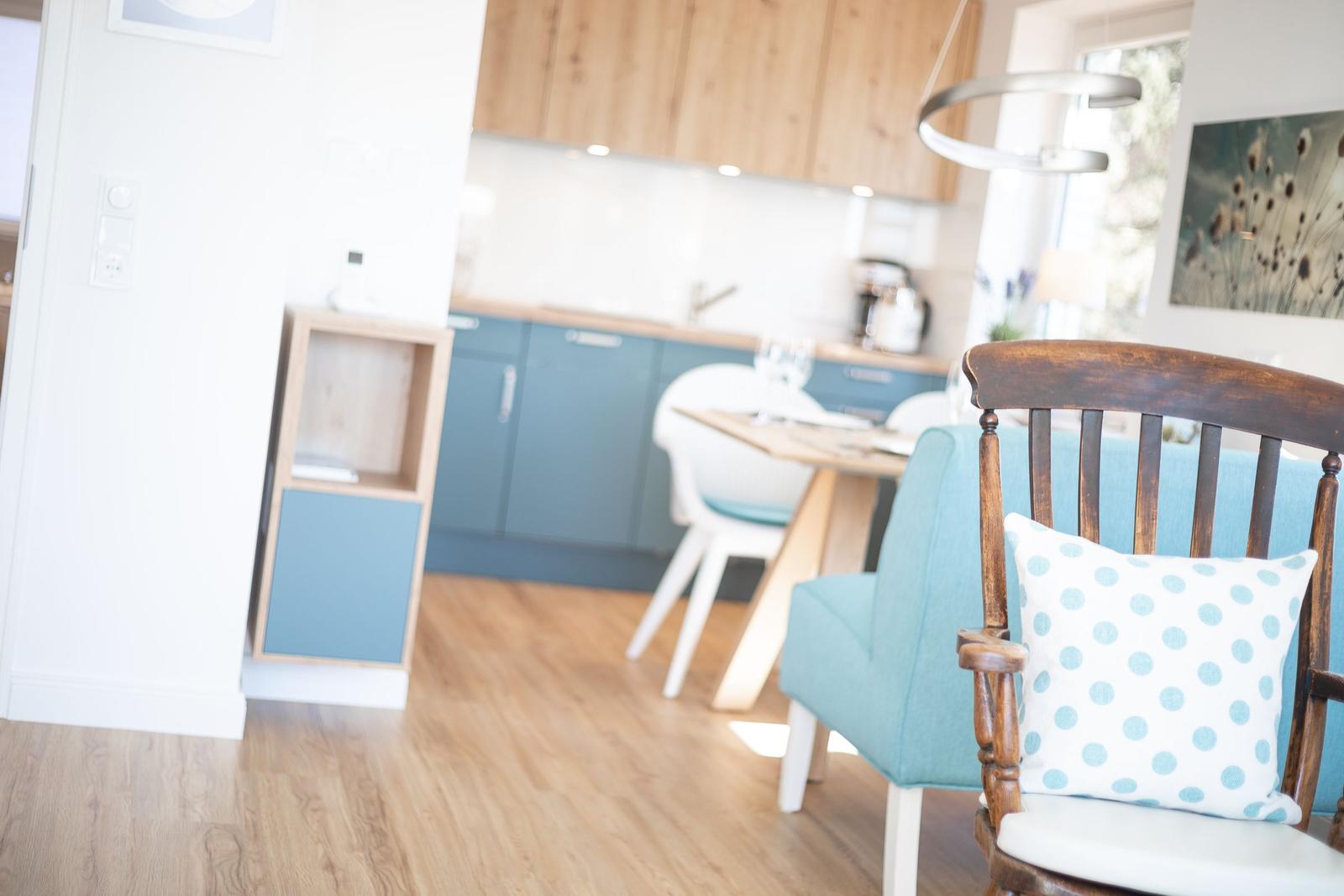 Dining area with wooden floor and blue kitchen in the background.