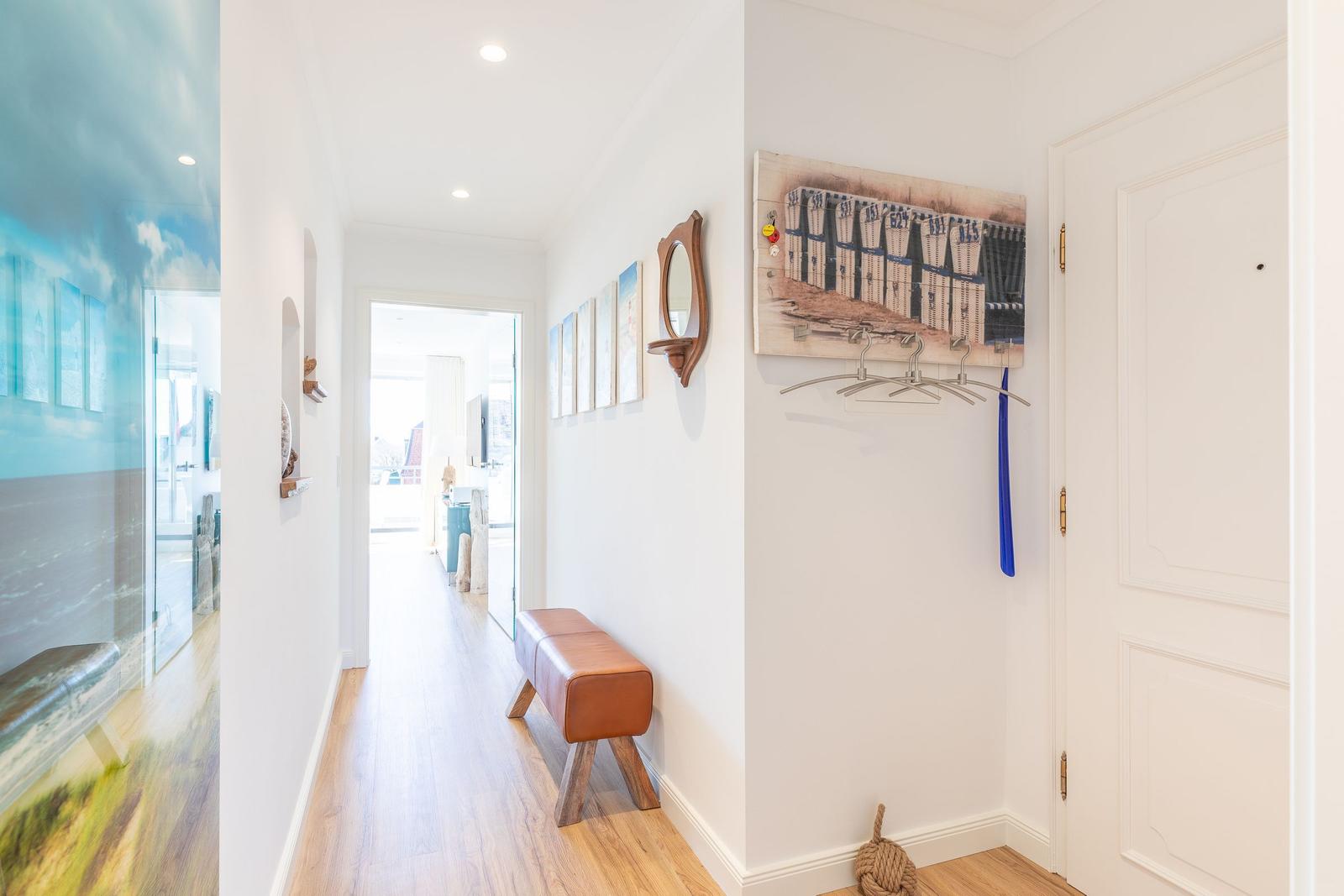 Hallway with wooden floor, wall art, and coat hooks on the wall