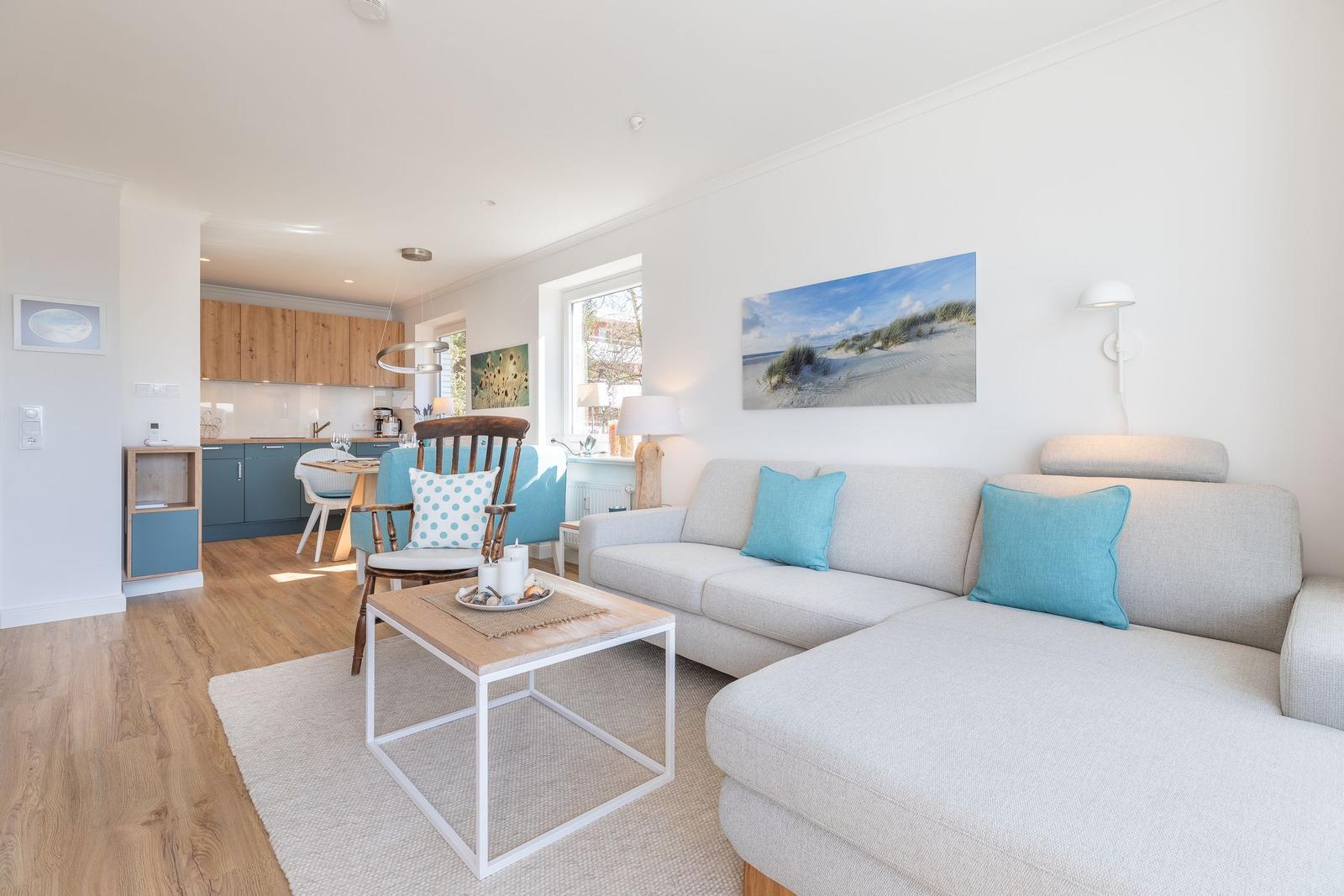 Living room with sofa, coffee table, and kitchen area in the background.