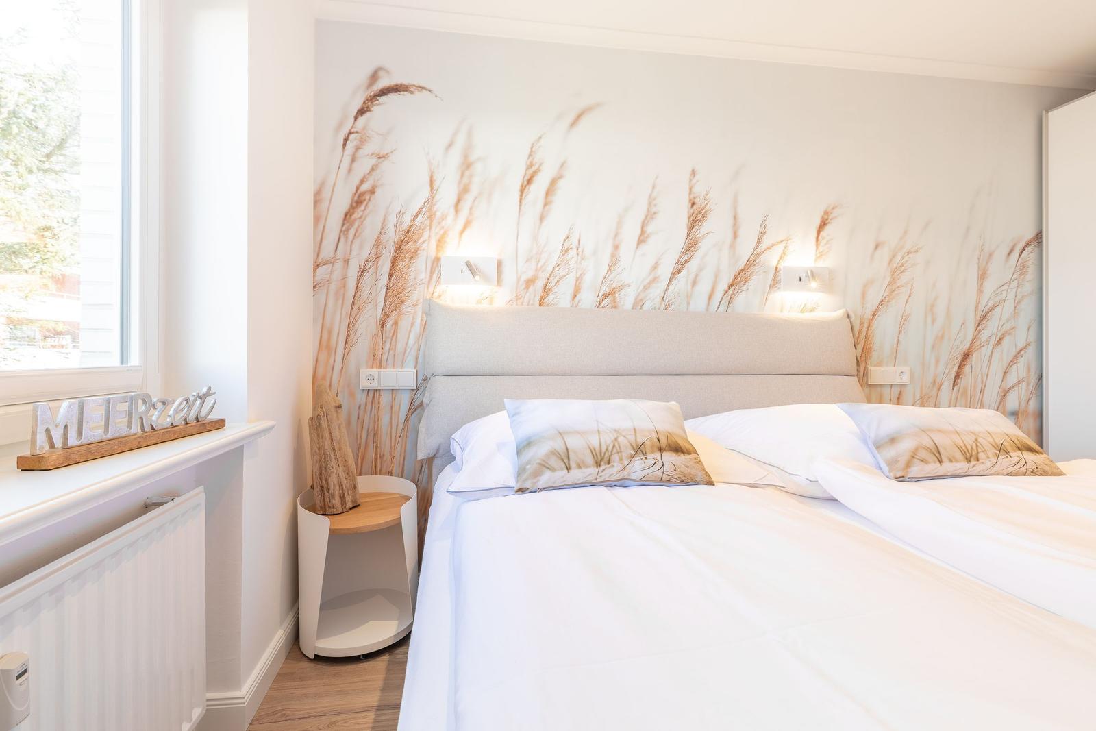 Bedroom with bed, wall mural, and window. A wooden object is on the windowsill.