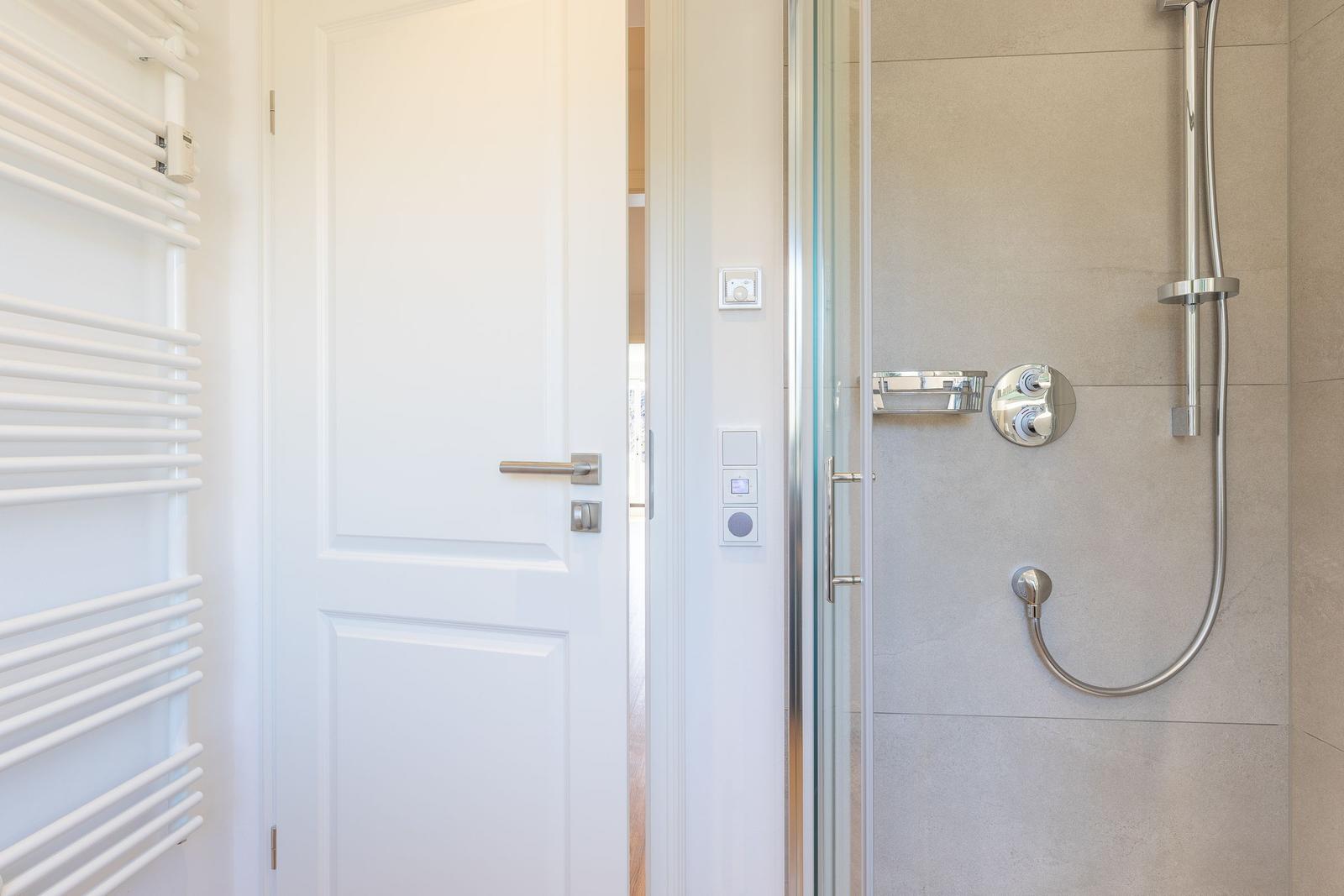 Shower with glass enclosure, showerhead, and wall-mounted heater.