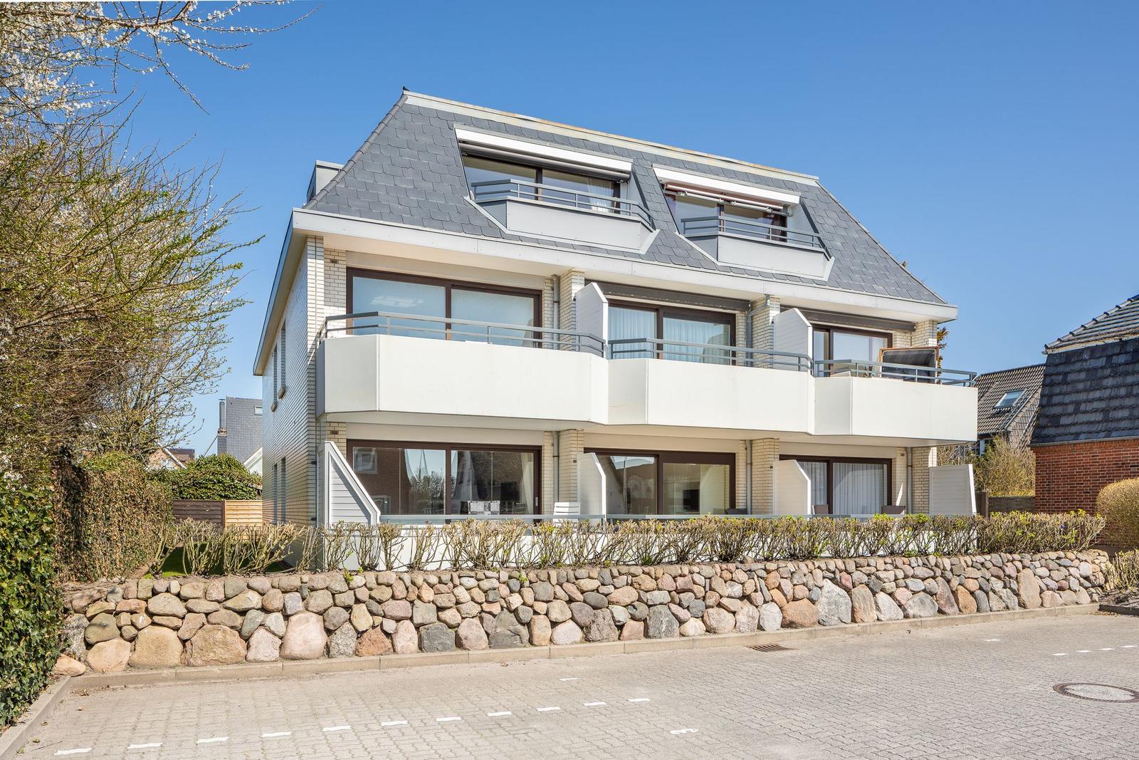 Modern villa with balconies and stone wall. Large windows and dormer windows.