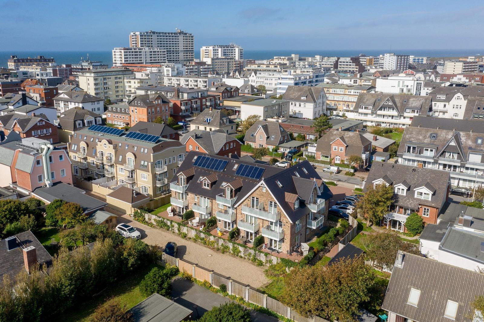 Haus mit Solaranlagen und Garten, Blick auf Stadt und Meer.