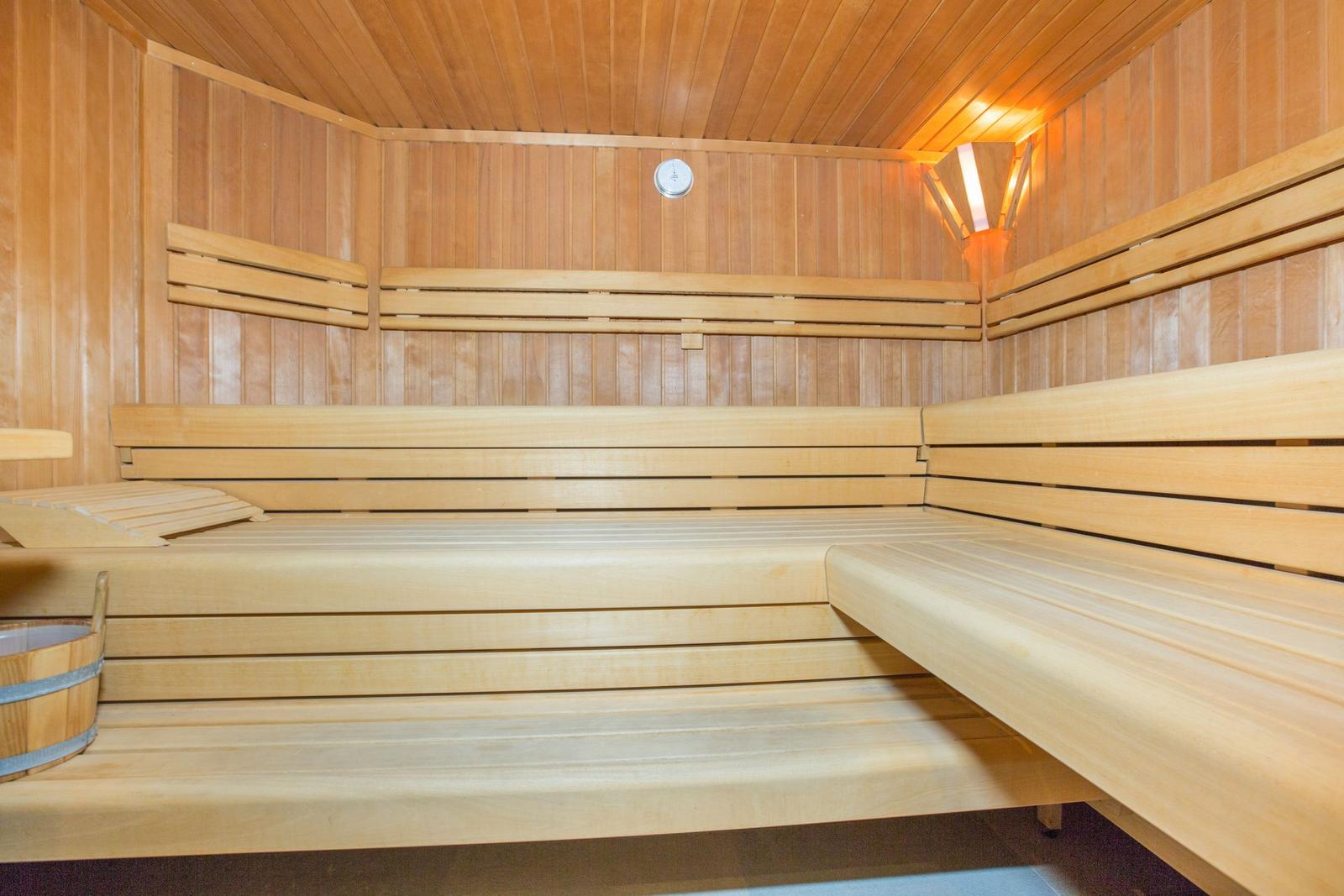 Holzsauna mit mehreren Sitzbänken und einem Eimer.