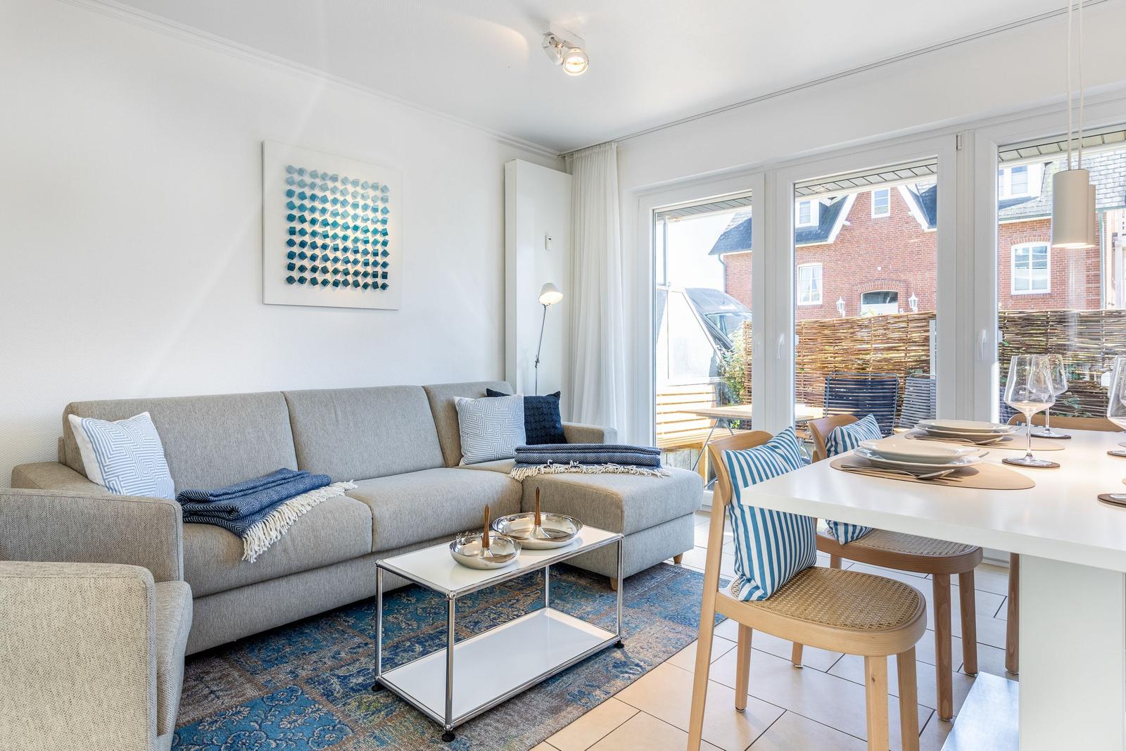 Wohn- und Essbereich mit Sofa, Tisch und Blick auf Balkon.