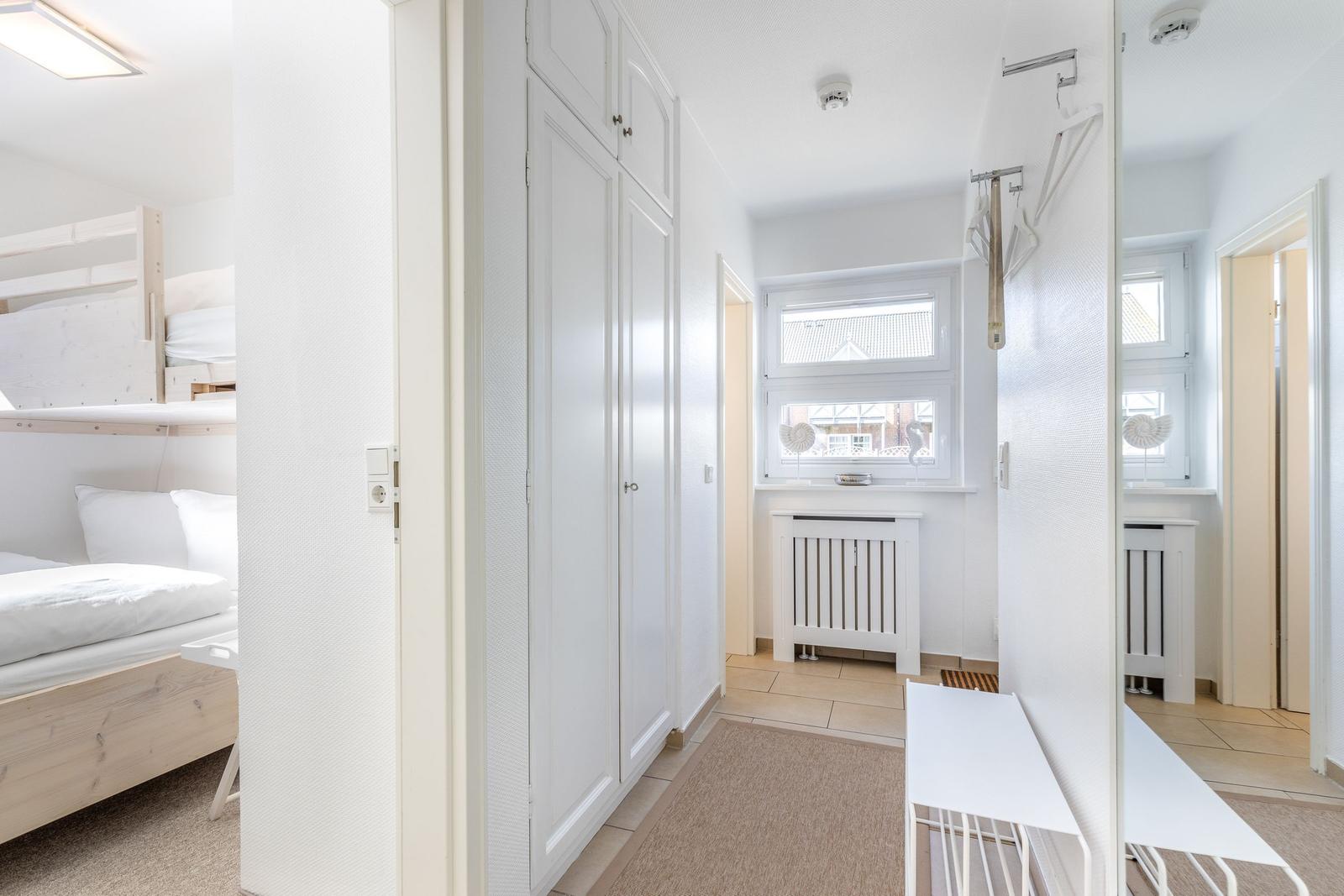 Flur mit Kleiderschrank, Fenster und Badezimmer. Links Schlafzimmer mit Doppelstockbett.
