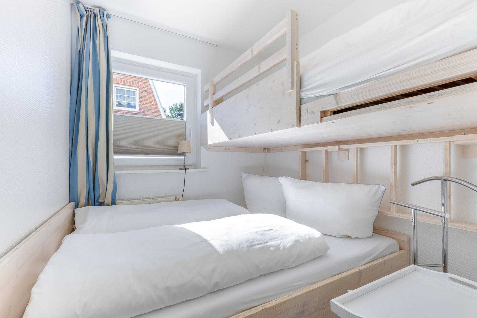 Zimmer mit Doppelbett und Hochbett, Fenster mit Vorhängen.