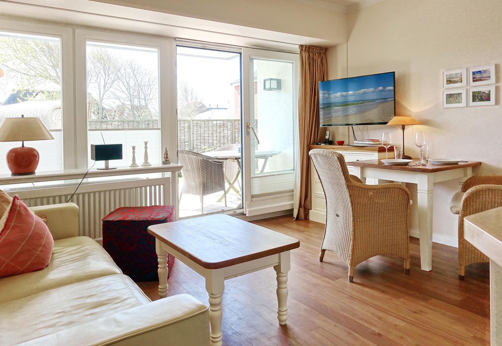 Living room with sofa, table, and TV. Access to terrace with tables and chairs.