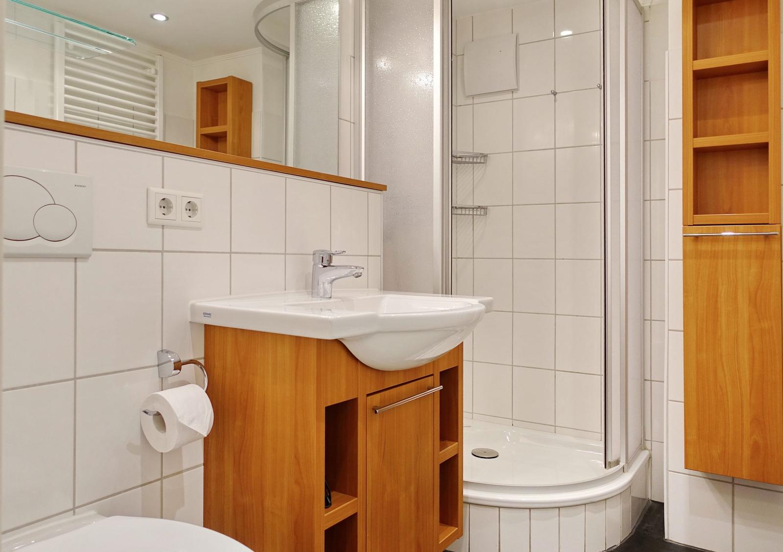 Bathroom with sink, shower, and wooden cabinets.