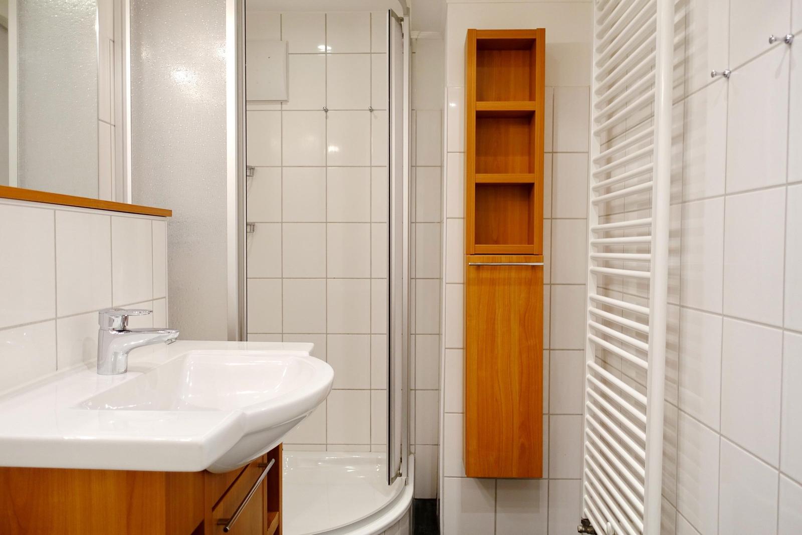 Bathroom with shower, sink, and wooden cabinets.