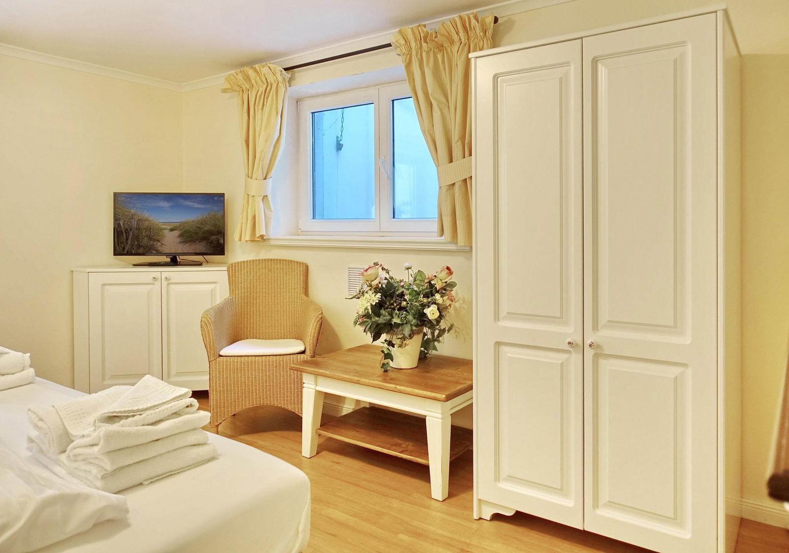 Bedroom with bed, wardrobe, armchair, and TV.