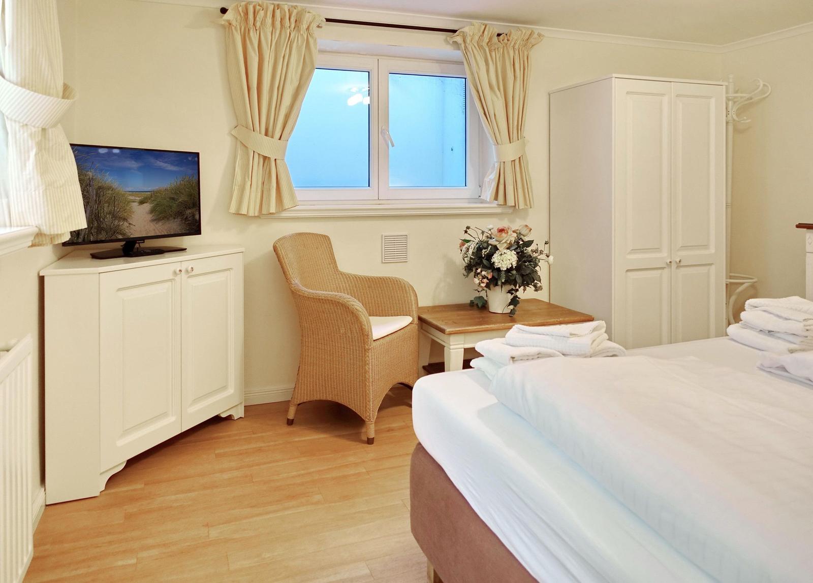 Bedroom with bed, TV, chair, and window.