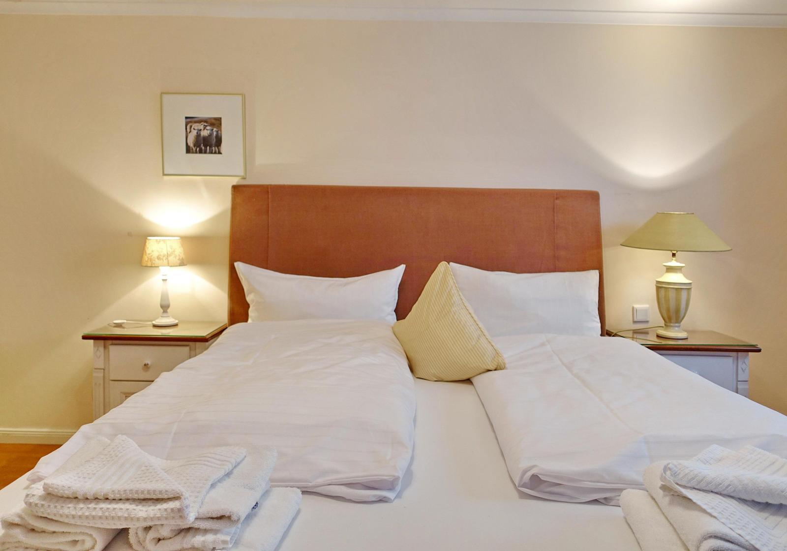 Double bed with white linens, two nightstands with lamps, and a picture on the wall.