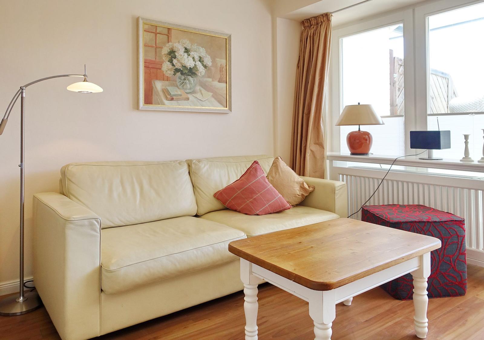 Living room with cream sofa, wooden table, and windows with curtains.