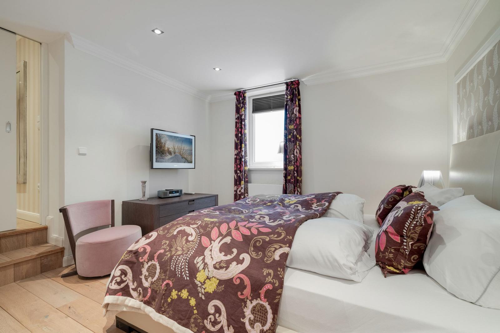 Bedroom with bed, TV, and window with curtains.