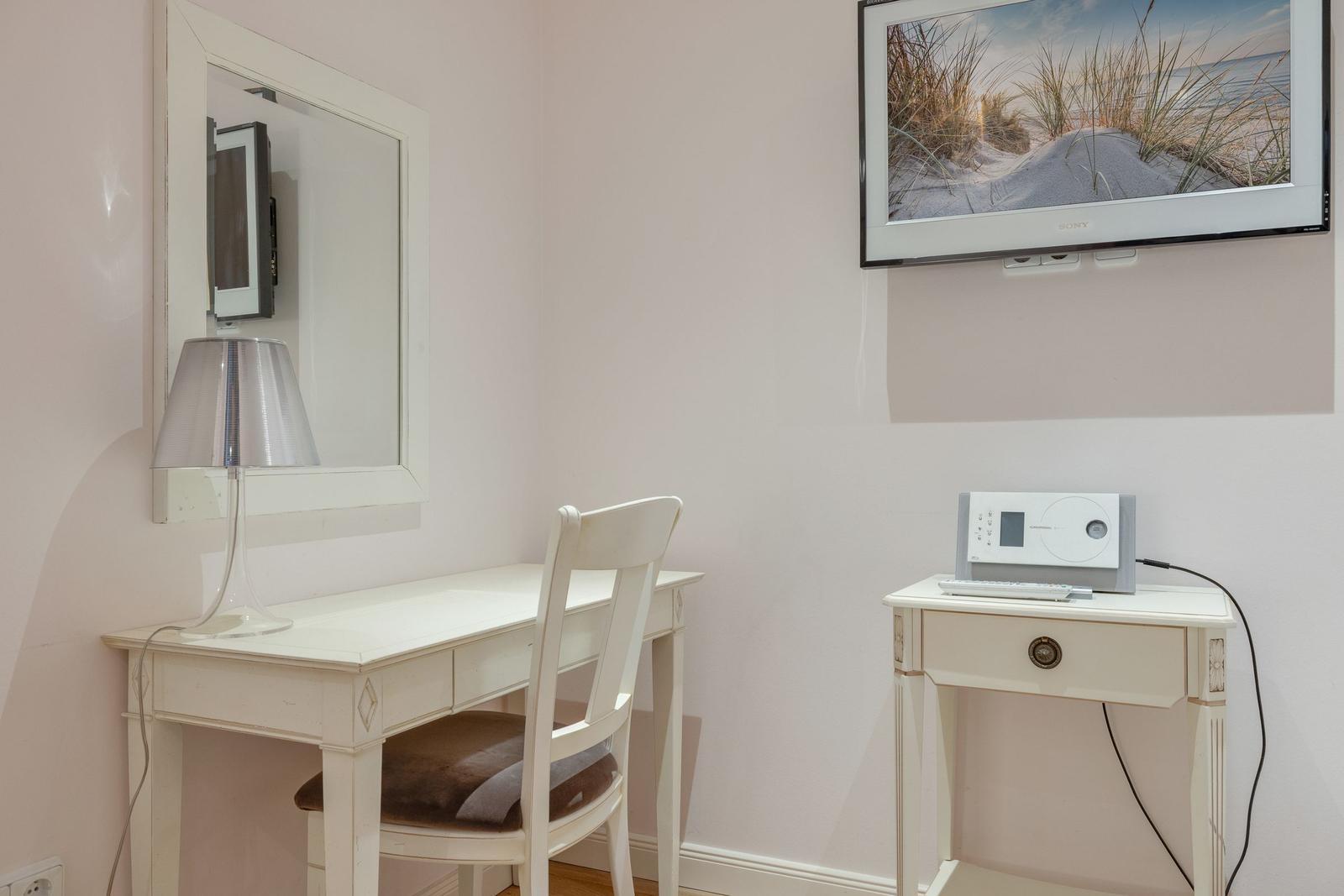 Desk with chair, mirror, lamp, and wall-mounted TV