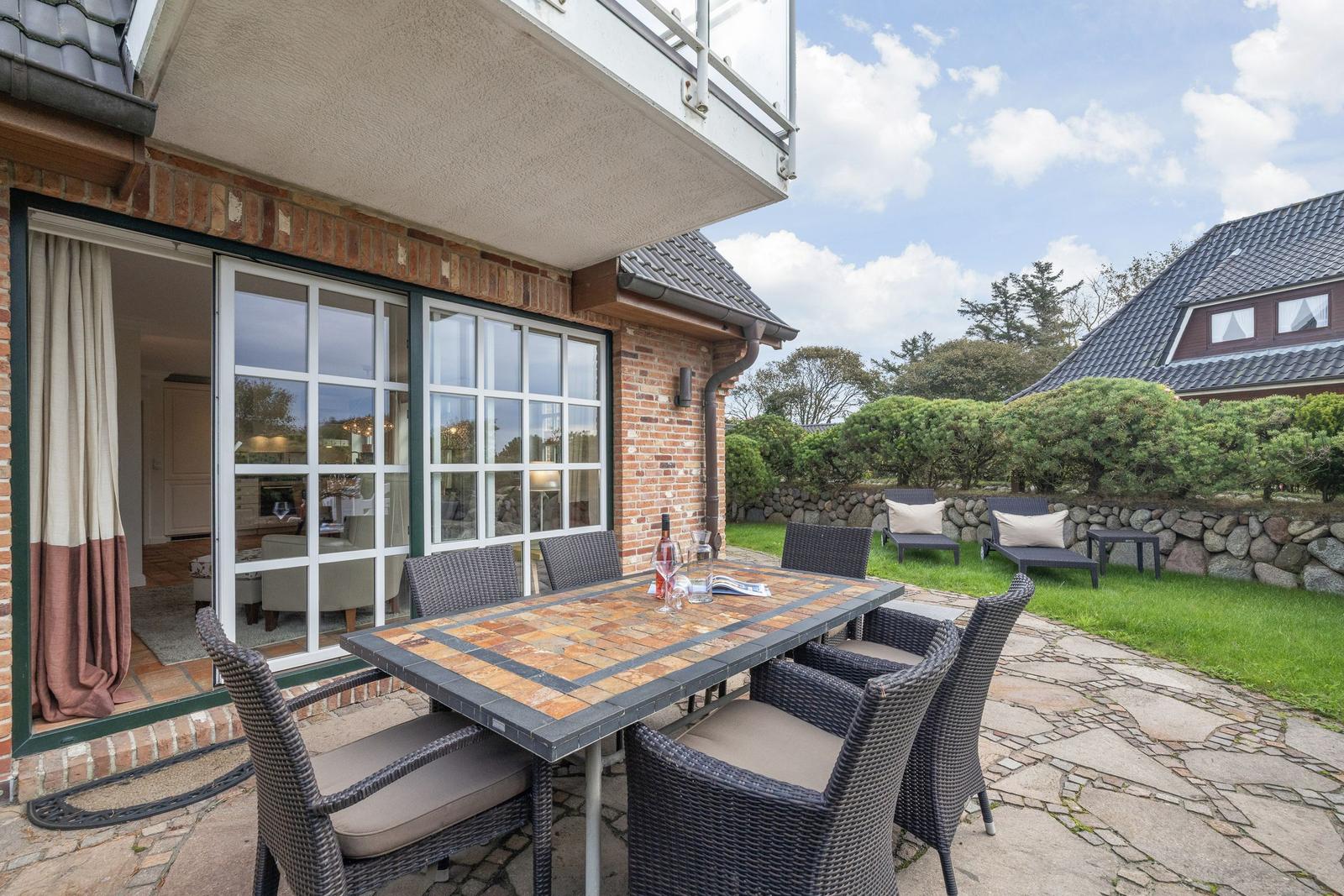 Terrace with dining table and chairs, view into the house and garden.