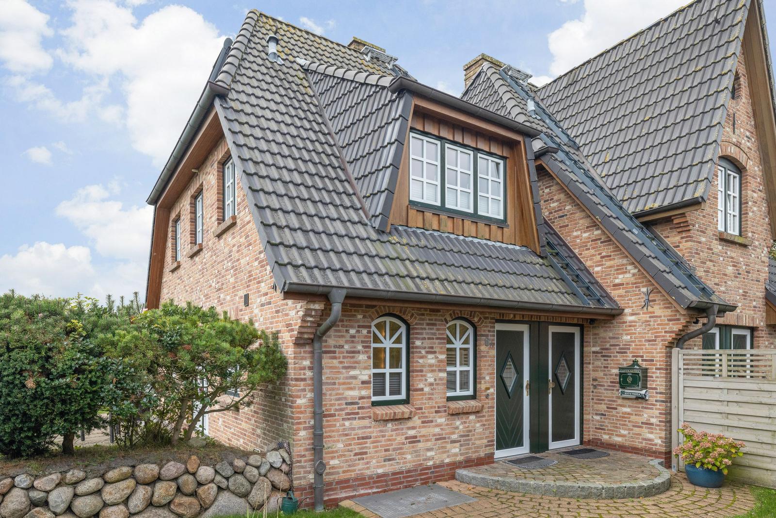 House with brick facade, dormer windows, and green front door.