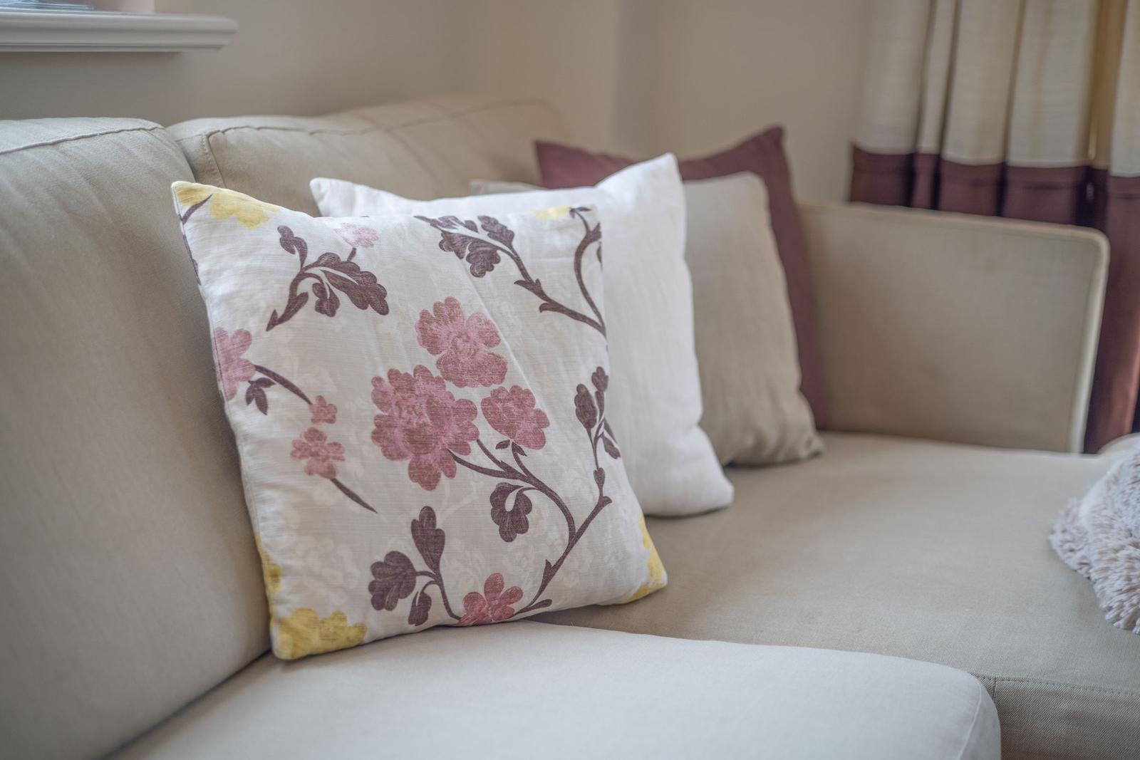 A sofa with cushions in floral patterns and neutral colors.