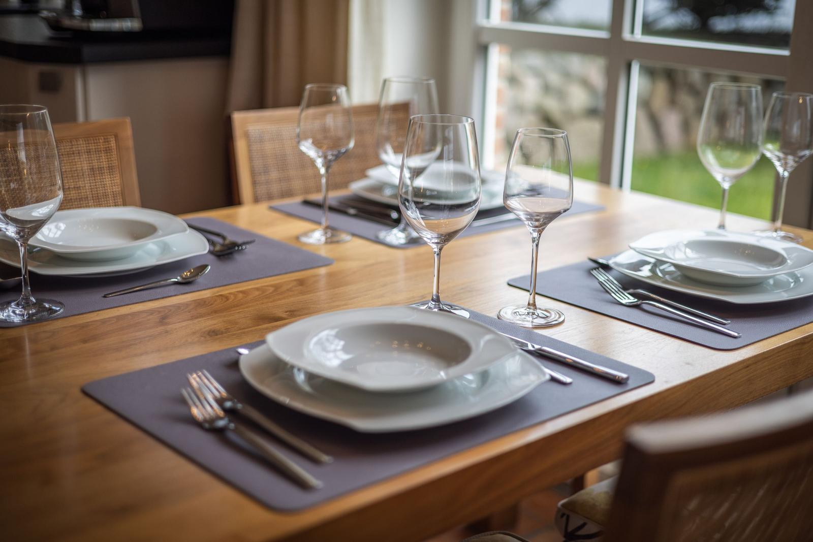 Wooden table with set places and view of the garden.