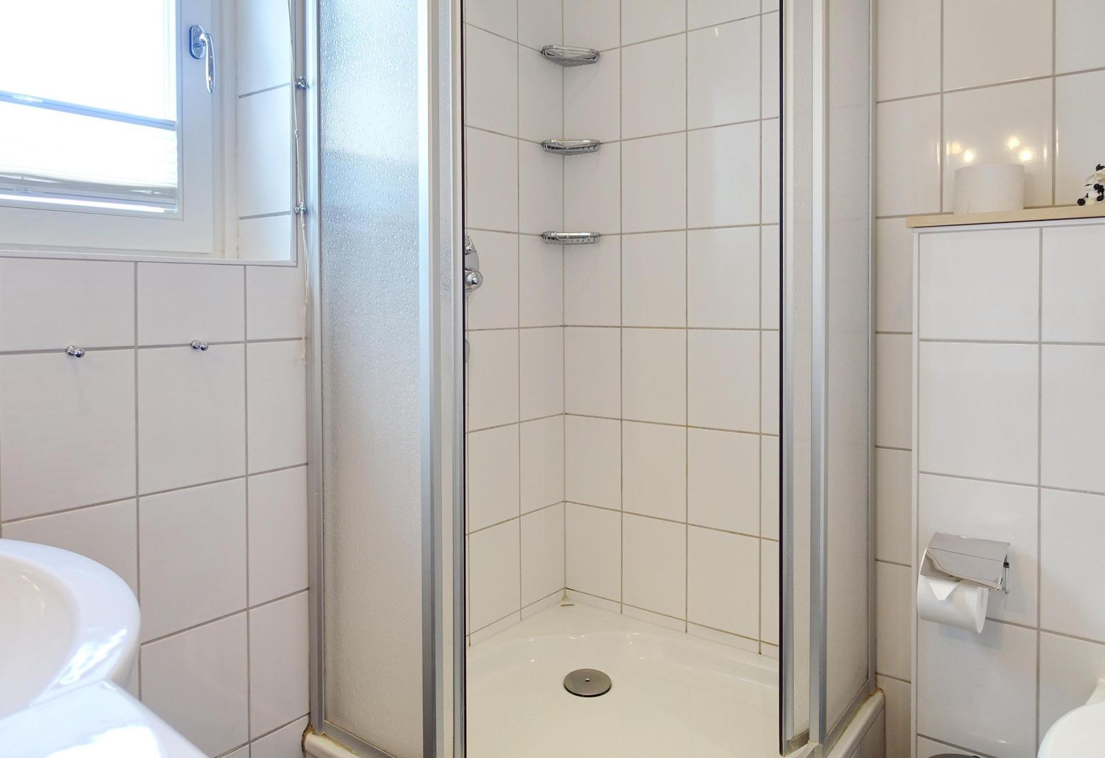 Badezimmer mit Duschkabine, Waschbecken und Toilette.