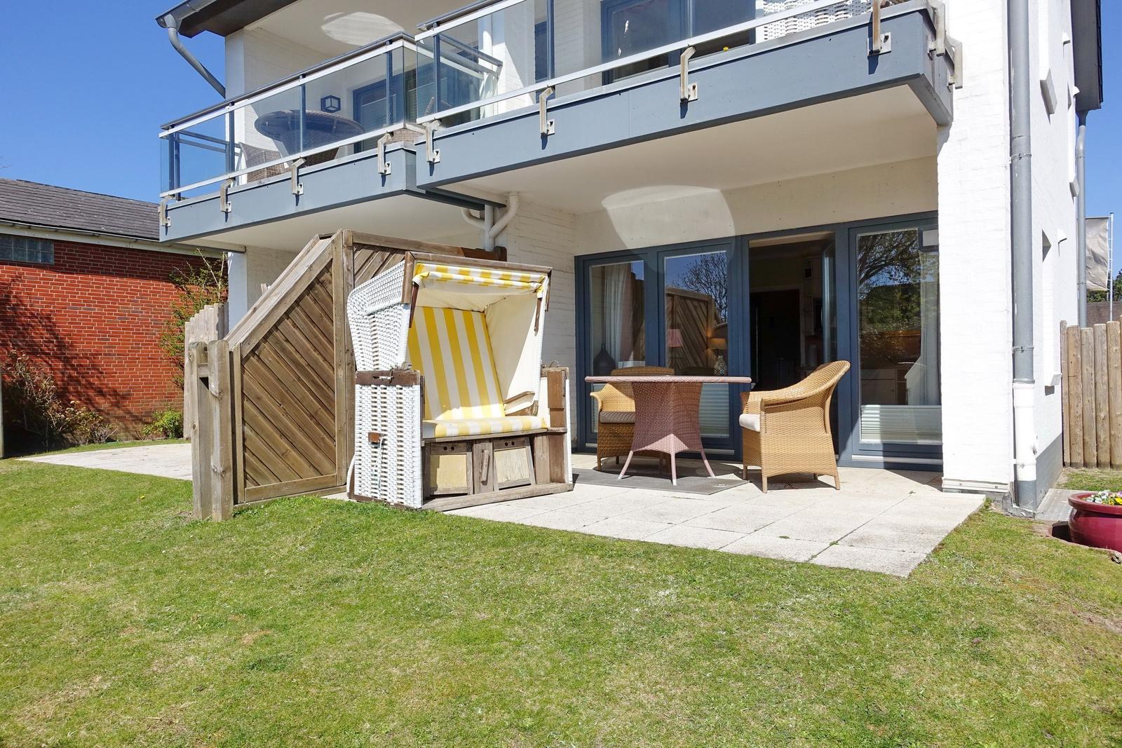 Hinterhof mit Garten, Liegestuhl und Terrasse mit Sitzgelegenheiten.