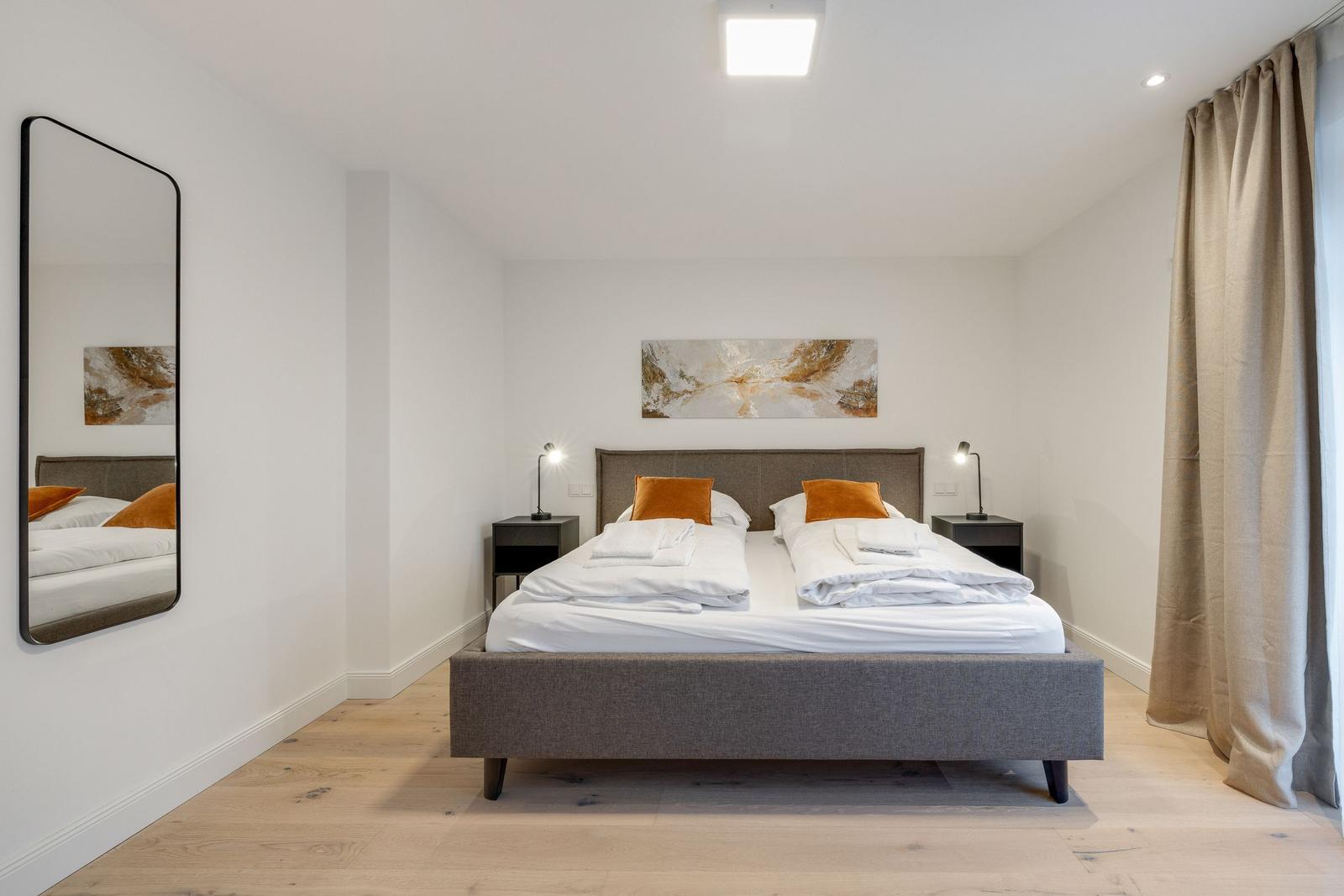 Bedroom with double bed, two nightstands, and wall mirror.