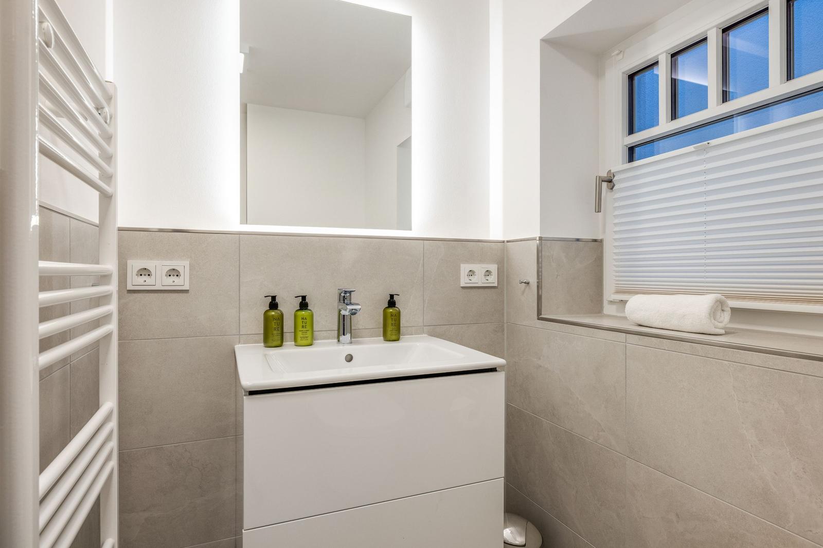Bathroom with sink, mirror, and window with blinds.