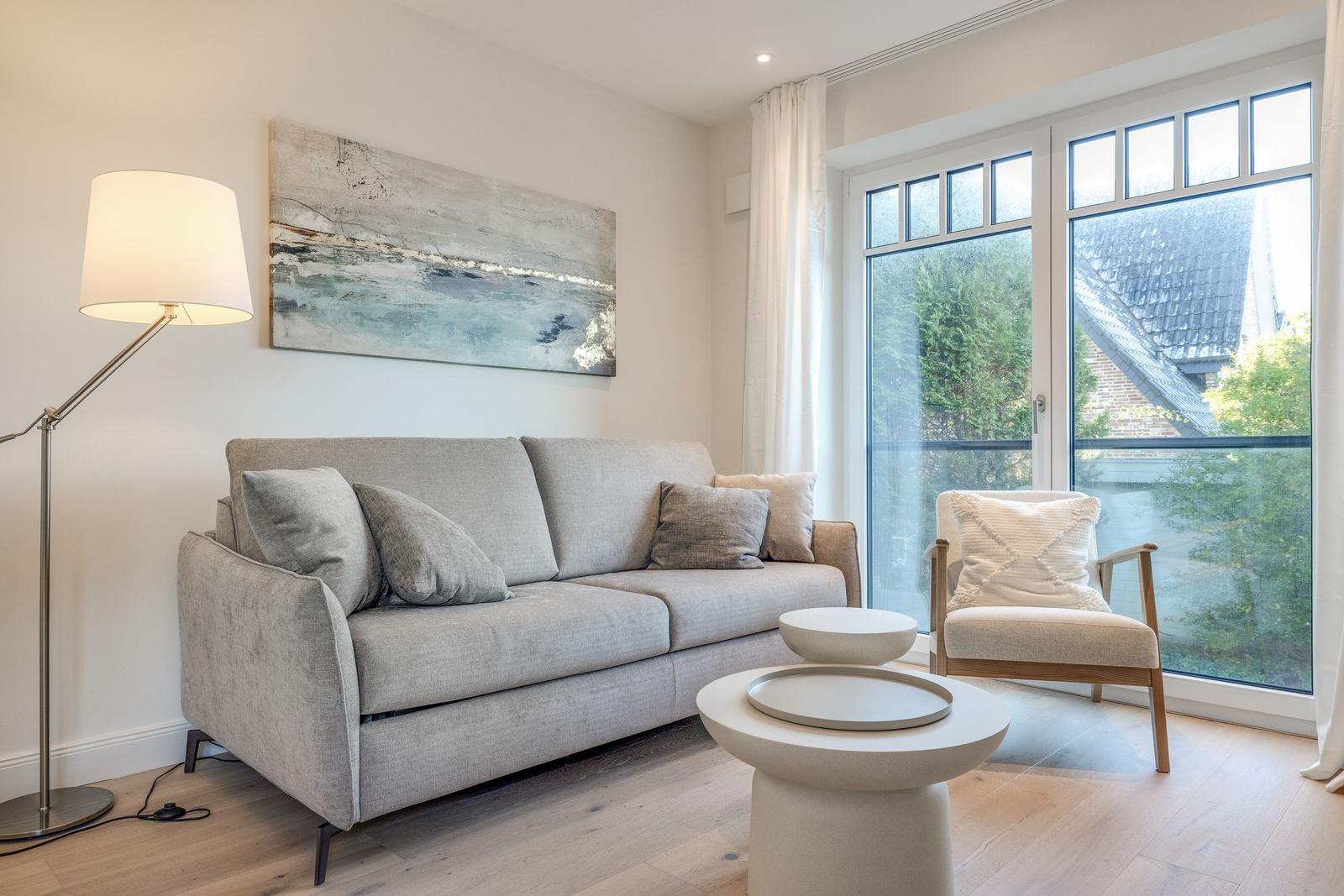 Living room with sofa, armchair, and large windows.