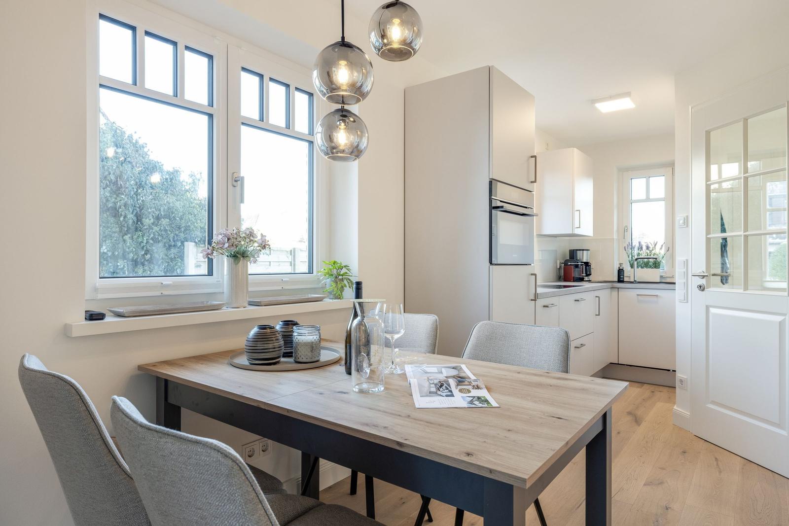 Dining area with table, chairs, and view of the kitchen.