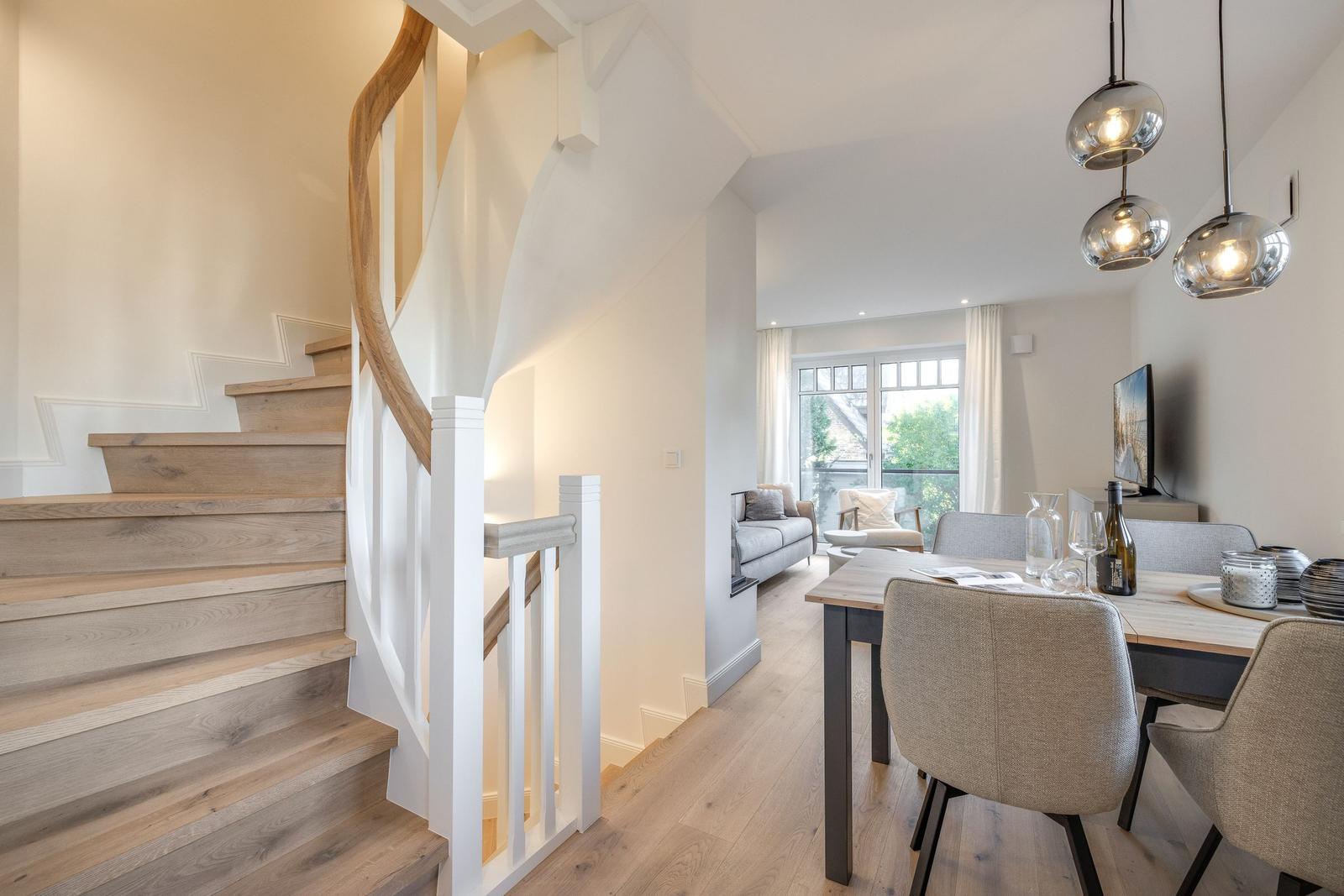 House with dining area, living area, and wooden staircase with curved handrail.