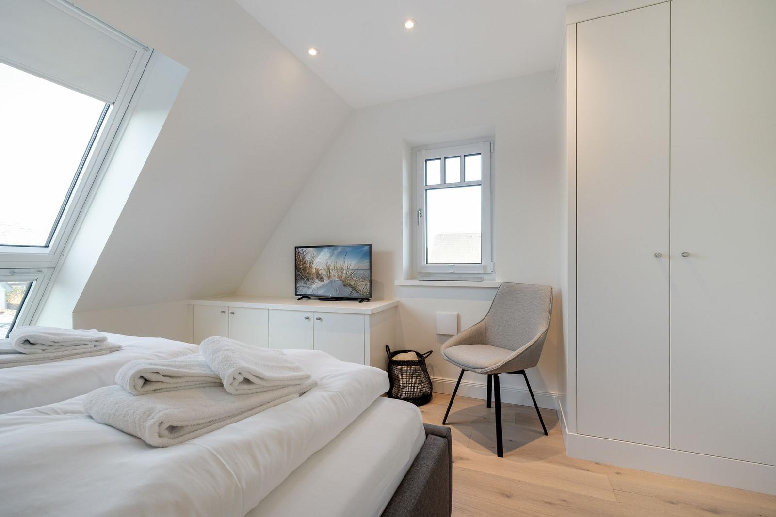 Bedroom with skylight, bed, wardrobe, and chair.