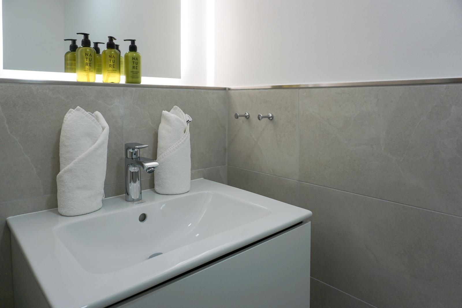 Badezimmer mit Waschbecken, Spiegel und Handtüchern