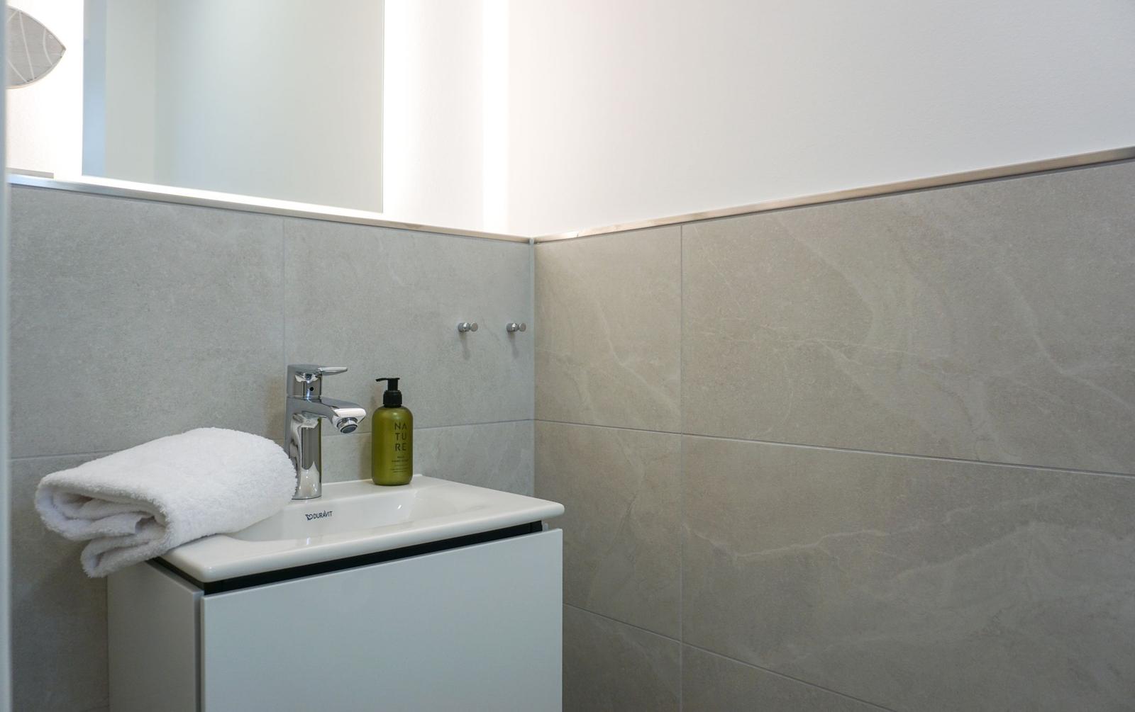 Bad mit Waschbecken, Spiegel und Handtuch