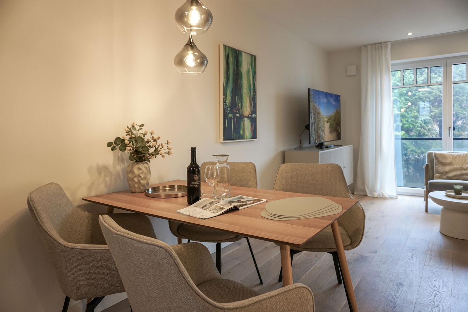 Essbereich mit Tisch, Stühlen und TV. Fenster mit Blick nach draußen.