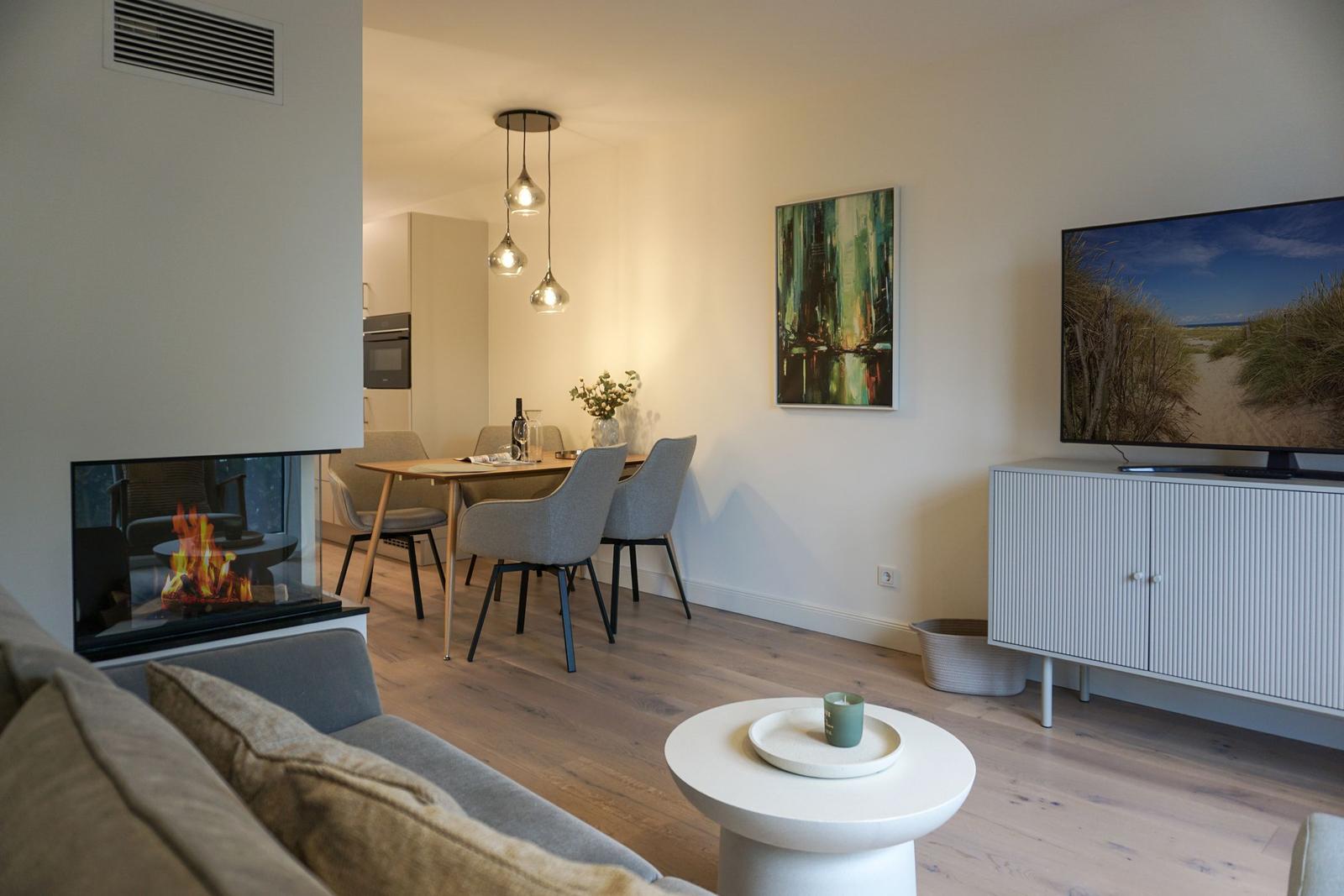 Wohnzimmer mit Kamin, Esstisch und Fernseher.