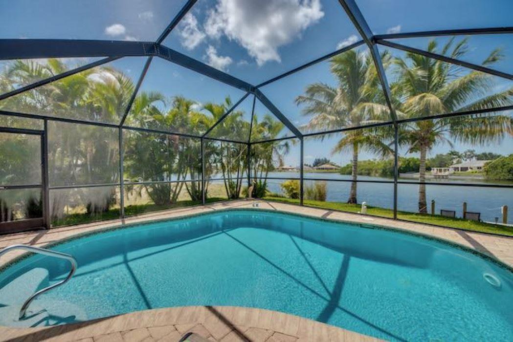 Geflügelte Pool mit Blick auf Wasser und Palmen.