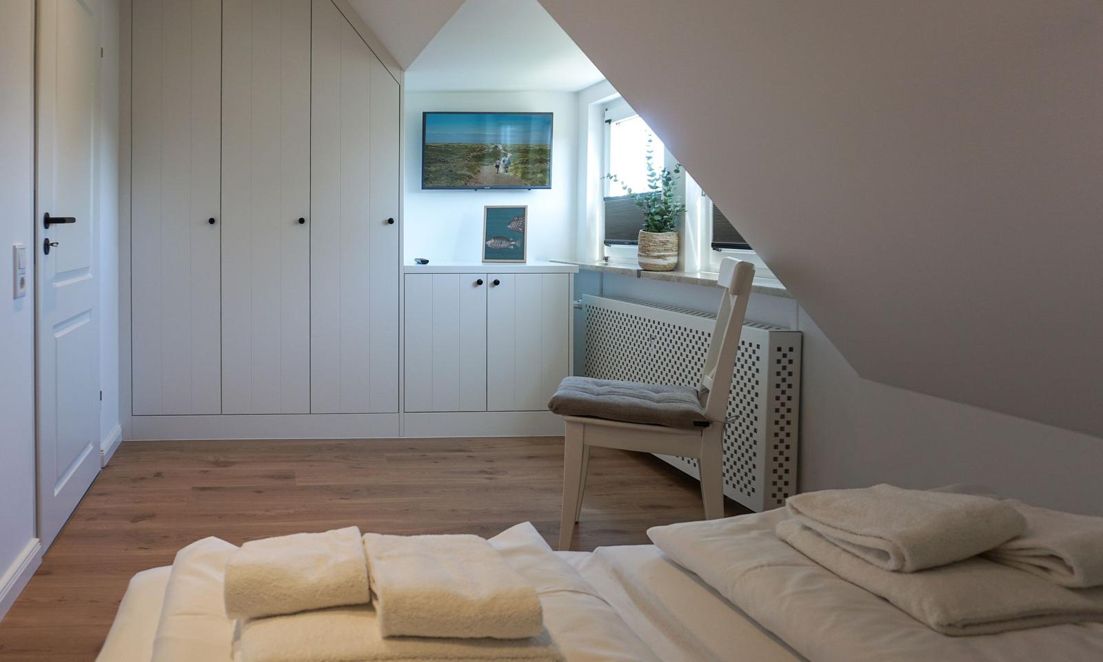 Bedroom with bed, wardrobe, and TV mounted on the wall.