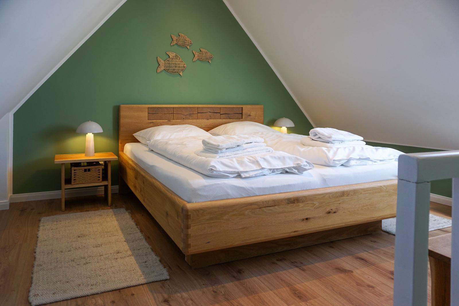 Bedroom with wooden bed, green wall, and fish decoration.
