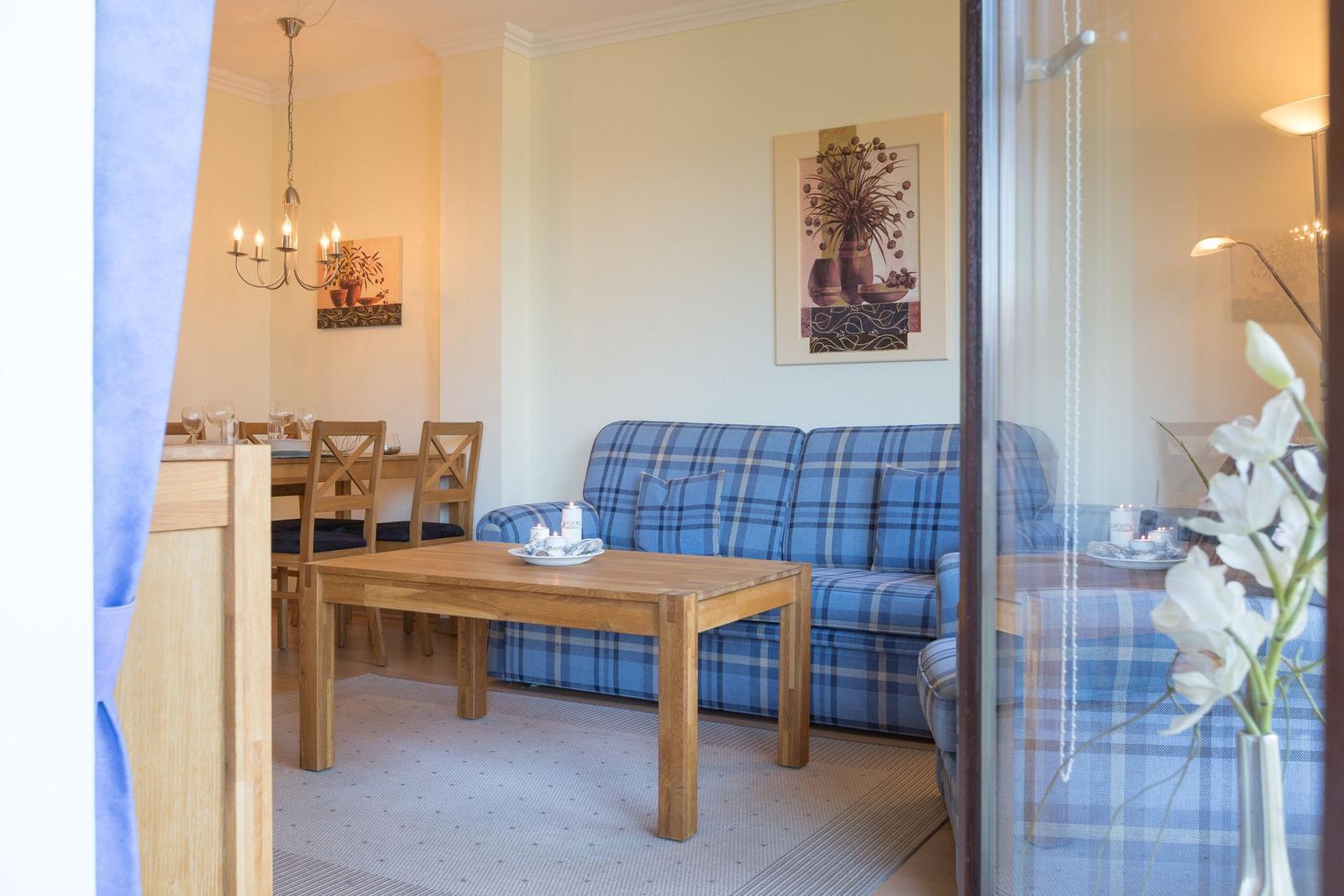 Living and dining area with blue checkered sofa and wooden table.
