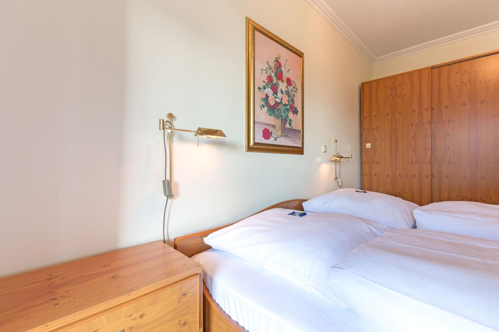 Bedroom with double bed, wooden closet, and wall painting with flowers.
