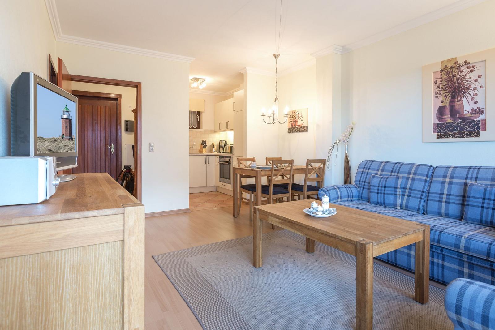 Living and dining area with blue checkered sofa and wooden table.