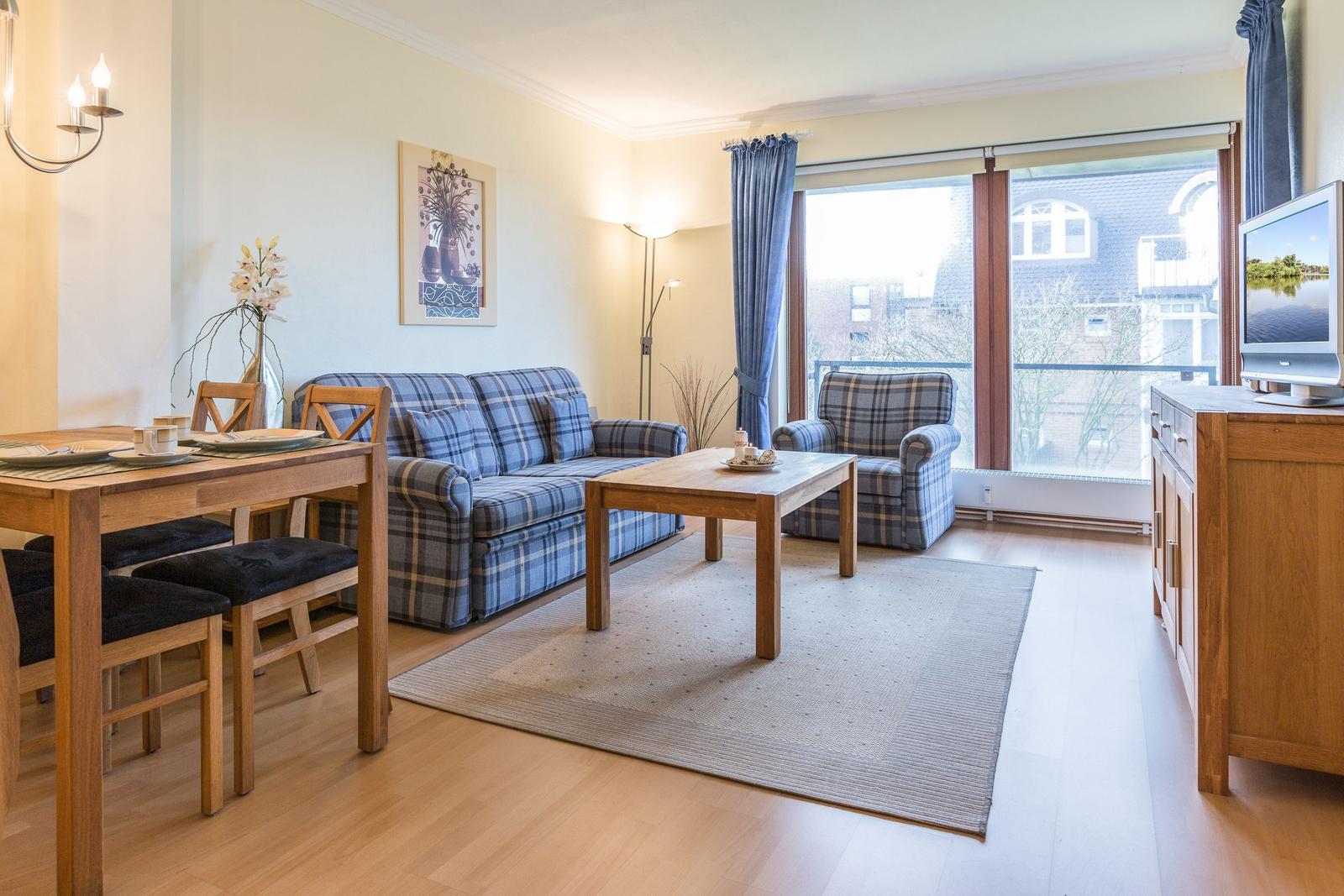 Living and dining area with sofa, table, and TV.