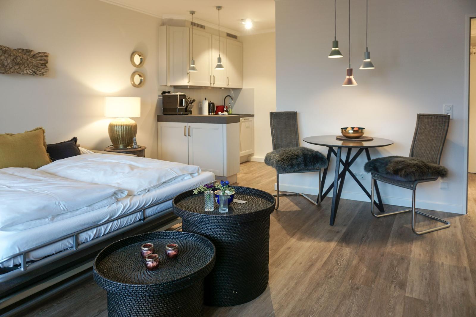 Schlafzimmer mit kleiner Küche und Essbereich mit Tisch und zwei Stühlen.