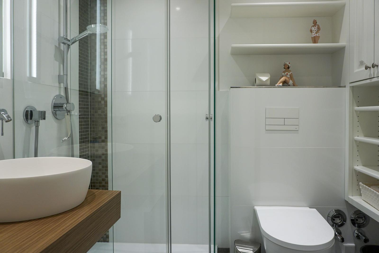 Badezimmer mit Dusche, Waschbecken und Toilette. Regal mit Figuren.