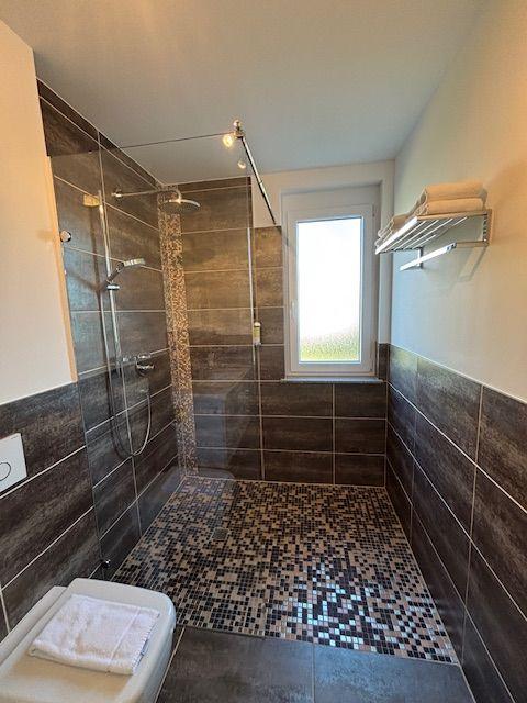 Dusche mit Glaswand, Mosaikwand und Fenster