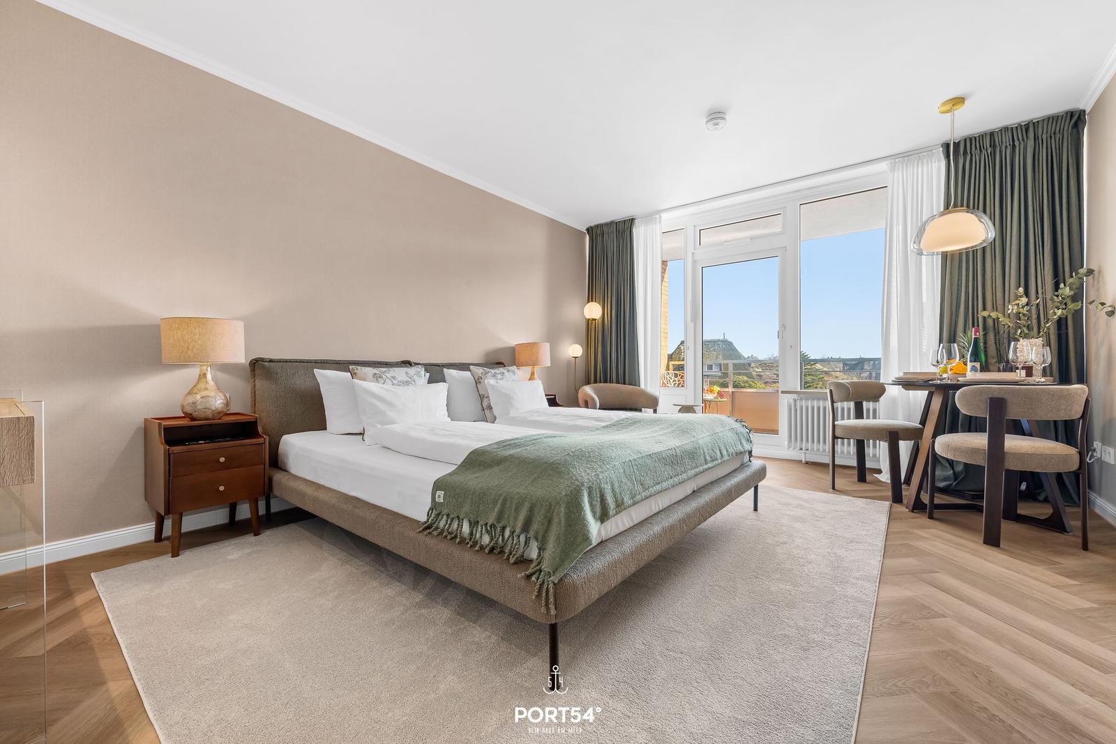 Bedroom with bed, nightstand, and view of balcony.