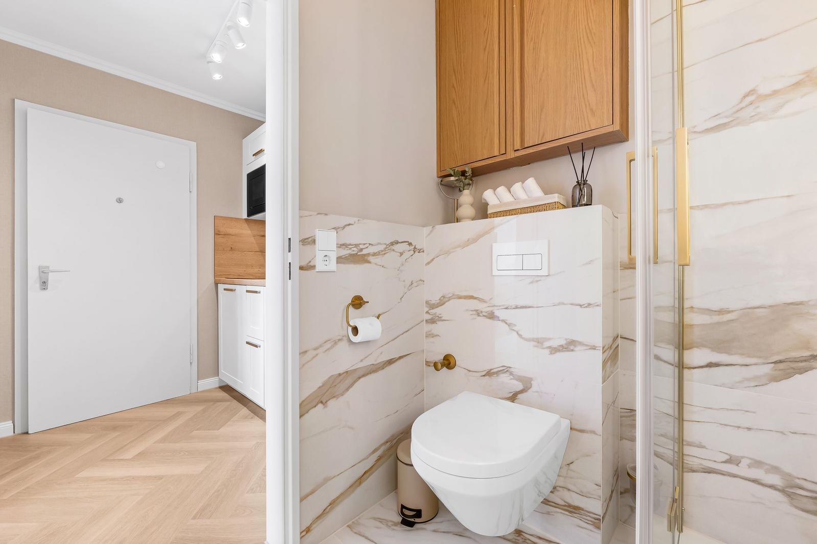 Bathroom with marble wall, toilet, and shower